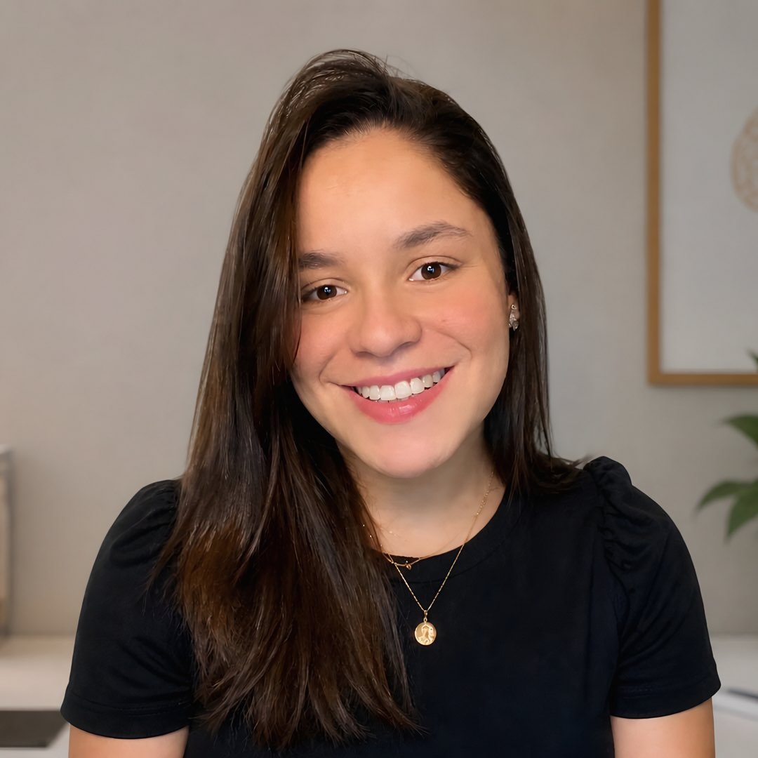 Carol sorrindo, de blusa preta e colar dourado